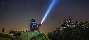 man met zaklamp zittend op grasveld