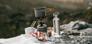 Gasbrander met pannetje en waterfles op een rots